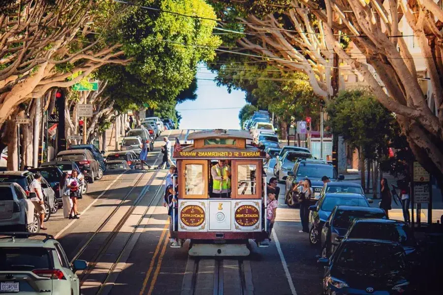 Um teleférico de 贝博体彩app se aproxima em uma rua arborizada.