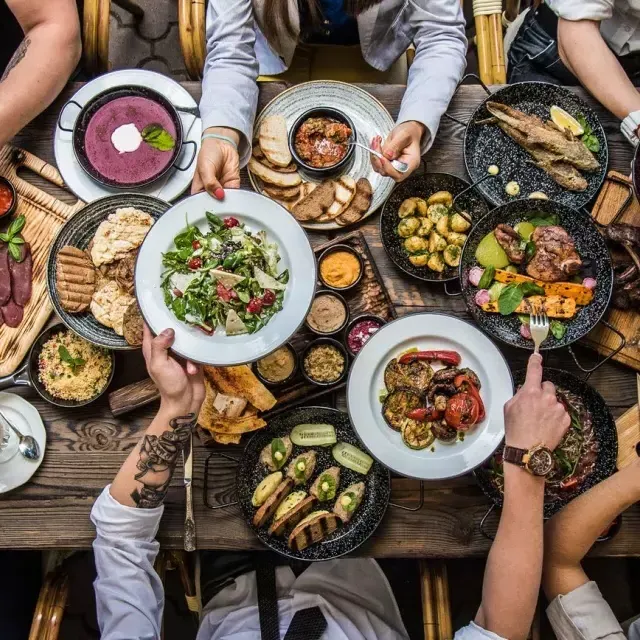 Persone sedute al tavolo da pranzo che condividono il cibo.